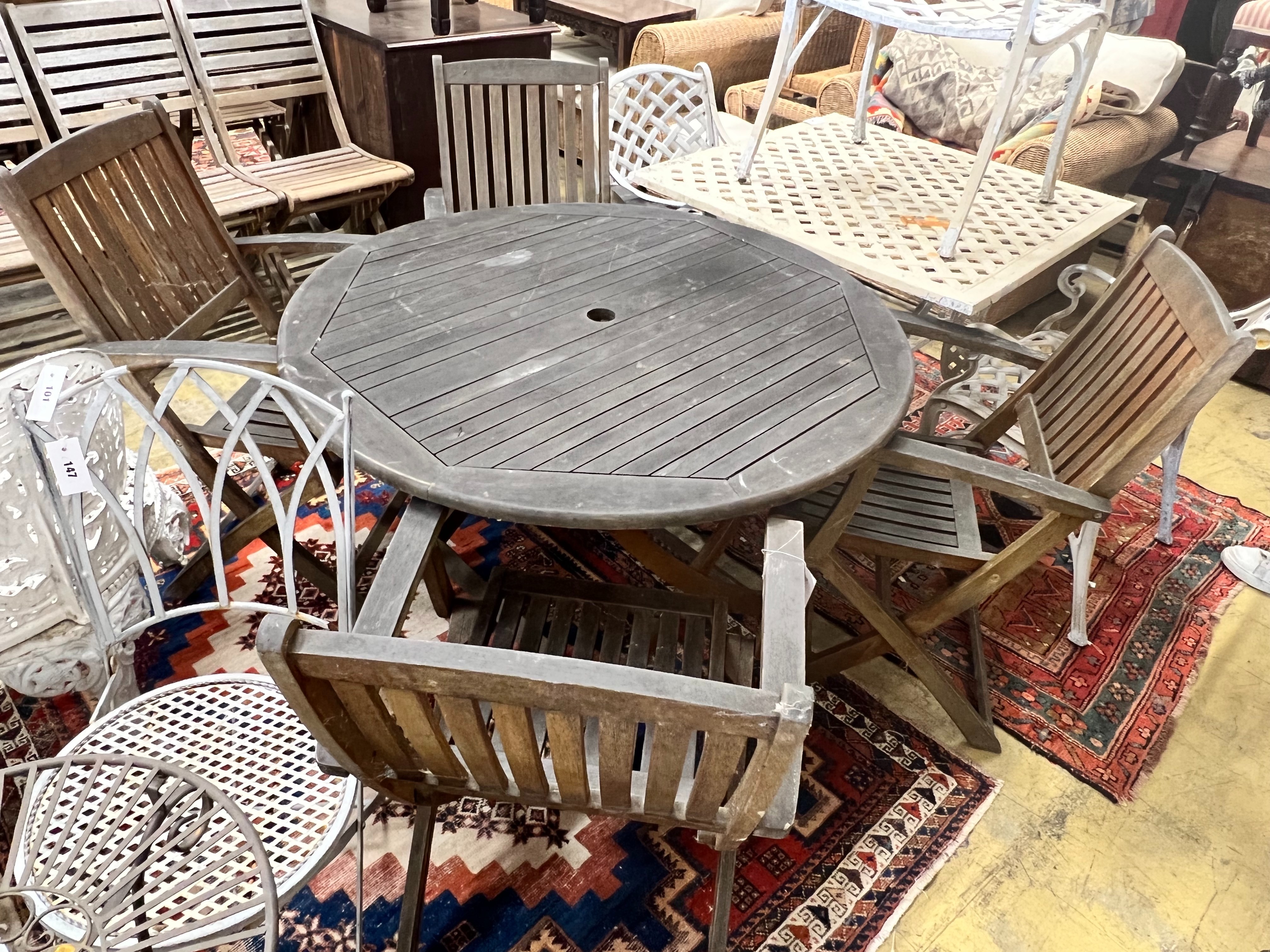 A circular weathered teak folding wooden garden table, diameter 110cm height 72cm, together with four elbow chairs